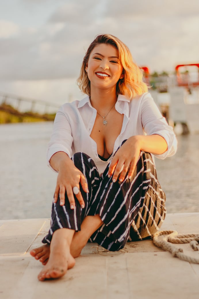 Woman in a White Shirt Smiling while Sitting on the Ground