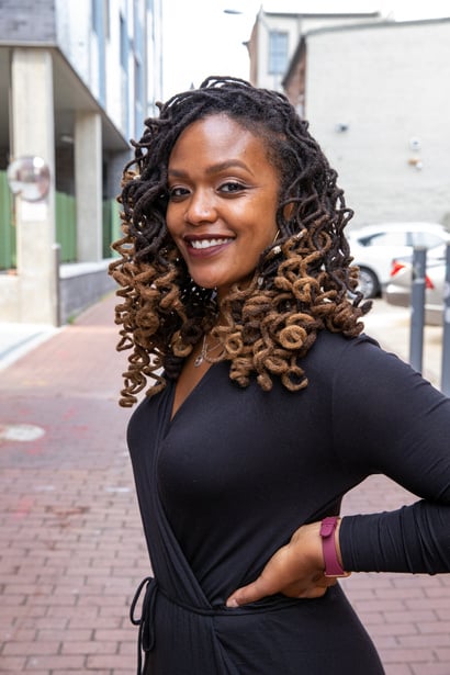 Smiling Woman in Black Dress with Curly Hair Outdoors